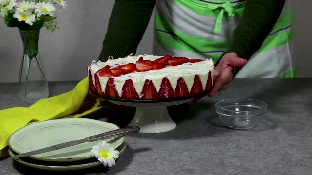 woman putting a strawberry cake or Fraisier on grunge gray table
