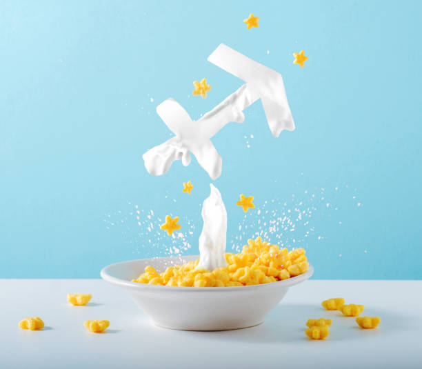 Zodiac sign Sagittarius made of milk levitates over breakfast plate of cornflakes and milk on blue background. Creative astrological postcard.