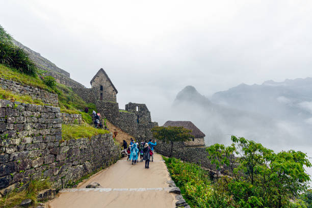 Cusco, Peru - January  2, 2020: The picture is taken from a trail. The ancient Inca citadel appears nestled high in the Andes mountains. The stone terraces and structures are visible, showcasing the intricate craftsmanship of the Inca architecture. Surrounding the site are lush green mountains in the mist.