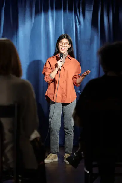 Photo of Comedian standing against blue curtains