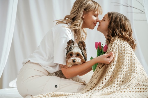 Mother's day. Cute dog. With daughter and flowers. At home together.