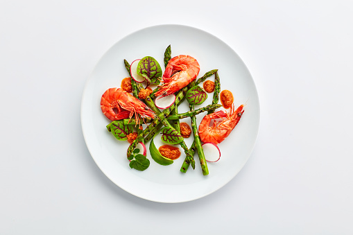 Food, dinner and above of seafood on plate for lunch, supper and meal preparation on white background. Ingredients, dish and top view of shrimp with cuisine for wellness, nutrition and healthy diet