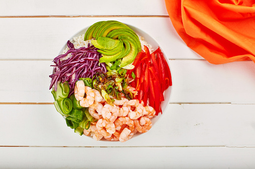 Poke bowl, shrimp and salad with restaurant background for healthy meal, hospitality and lunch menu. Top view of a white table or surface for food, colorful dish and avocado with Hawaiian cuisine