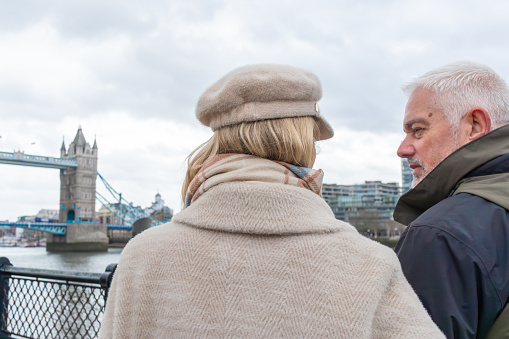 Senior couple talking whilst looking at Tower Bridge in London and the River Thames together