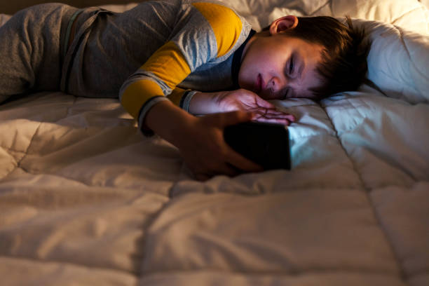 cropped shot of a young boy sleeping with a cellphone in hand at home. - iphone human hand iphone 5 blank zdjęcia i obrazy z banku zdjęć