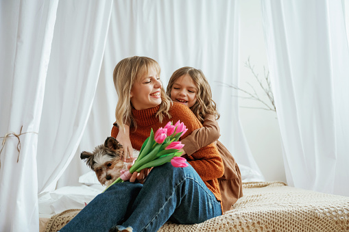 Flowers in hands. Mother's day concept. Female parent with daughter is at home.