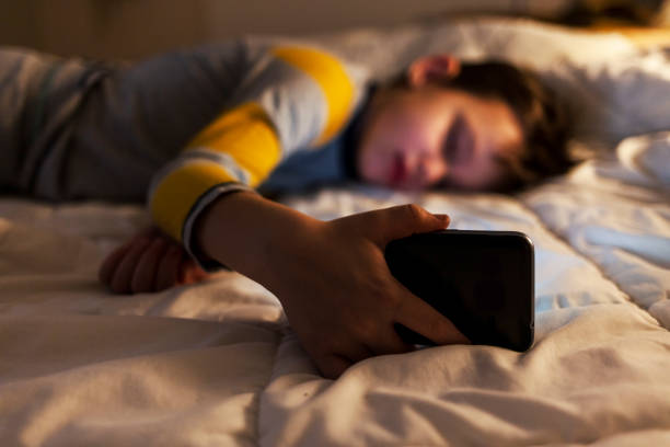 cropped shot of a young boy sleeping with a cellphone in hand at home. - iphone human hand iphone 5 blank zdjęcia i obrazy z banku zdjęć