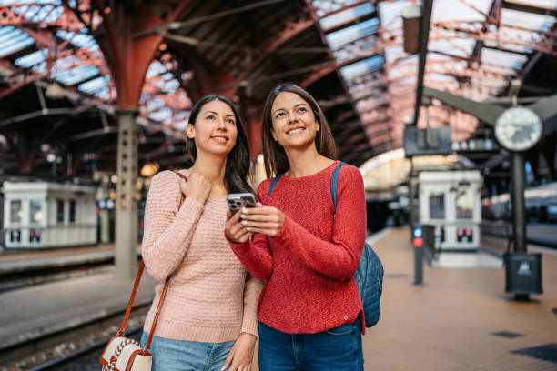 istock Two Female Friends Using A Phone While Waiting For A Train At The Railway Station In Copenhagen In Denmark 2047787746
