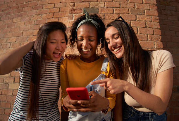 istock three women are standing next to each other looking at a cell phone 2047788299