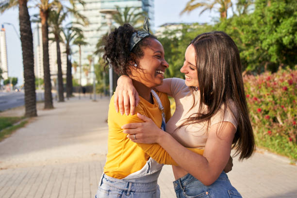 istock Two young women happily embrace on a sidewalk, surrounded by trees and plants 2047794272