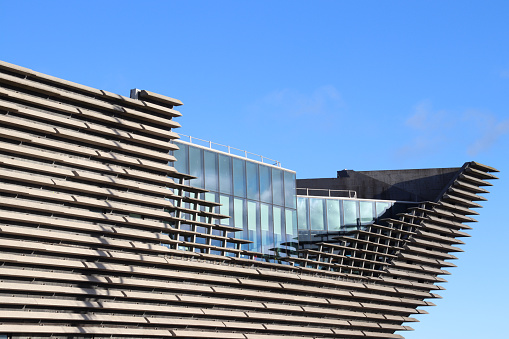 Side view of concrete slab structure and windows  of the V&A Museum in Dundee, Scotland, against blue sky