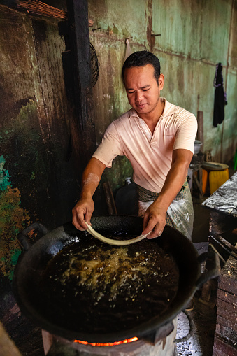 Burmese man preparing and selling fresh  Chinese “oil stick” doughnuts  on a local market in Bagan, Myanmar