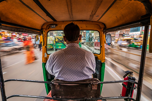 Indian man drives auto rickshaw (tuk-tuk) on streets of Jodhpur in Rajasthan, India.