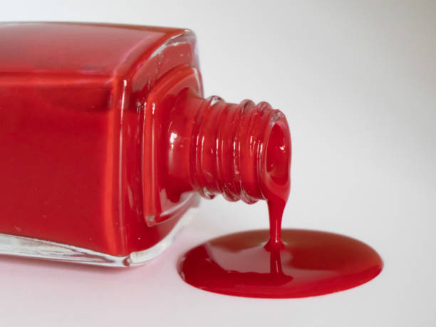 Close-up of a red nail polish spilled on a white surface