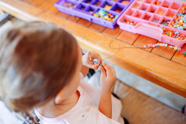 istock Little girl making bead bracelets 2047817869