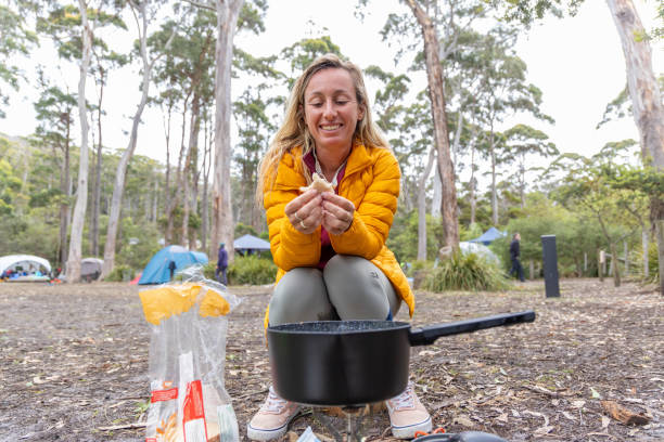 australian adventure: young woman masters the outback cuisine at campsite with a portable stove - australian culture hiking australia people fotografías e imágenes de stock