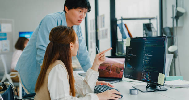 istock Asian manager instructs a new hire, demonstrating the collaborative spirit in a tech-focused office that values accessibility and sustainability. ESG sustainable business office. 2047829150