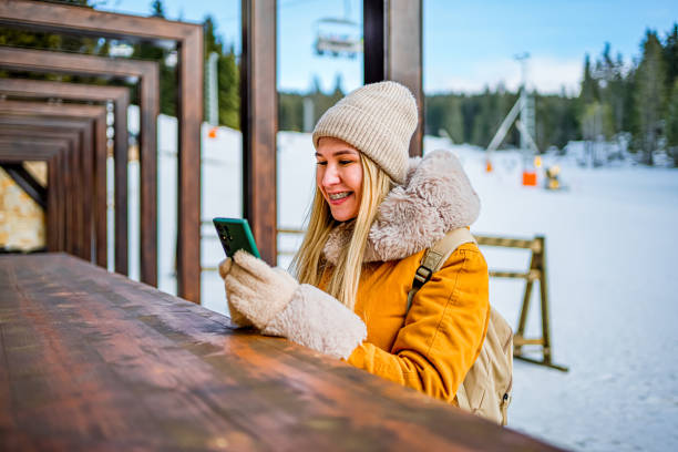 istock Young woman using phone at ski resort on mountain 2047835763