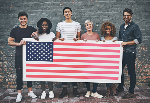 Happy, diversity and people with a USA flag for representation, support and branding. Smile, together and group of people with a poster to represent a country, show patriarchy and diverse environment