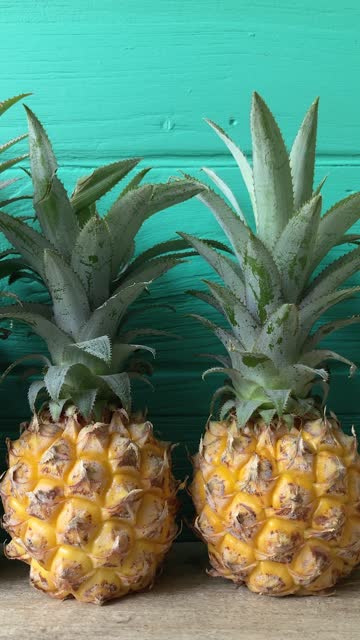 Row of pineapples against a turquoise background.