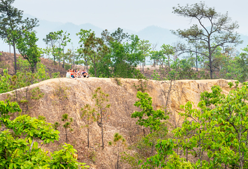 Pai,Mae Hong Son,Thailand-April 09 2023:Young travelers perched atop a distant precipice,in this naturally formed,eroded landscape and area of natural beauty,to enjoy sunset on steep,dangerous paths.
