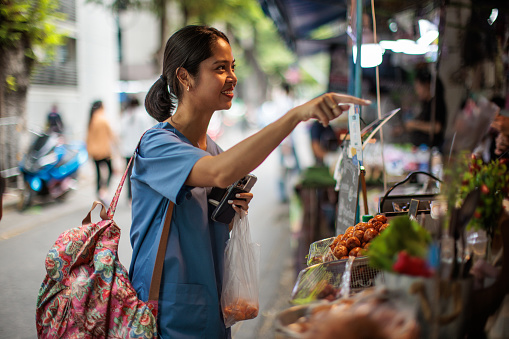 Woman healthcare worker buying lunch at the street market.