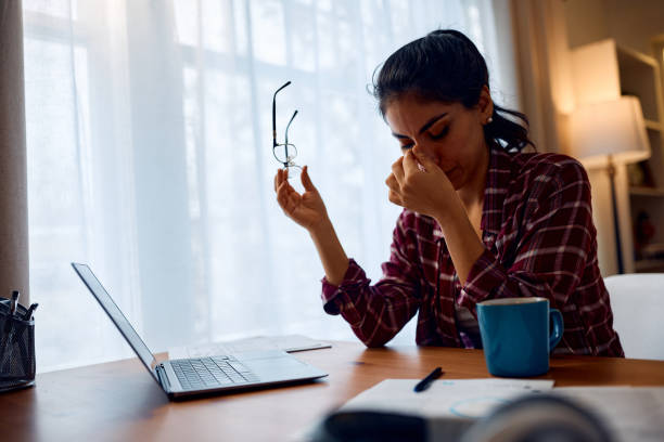 istock Stressed woman having a headache while working remotely on laptop at home. 2047875467