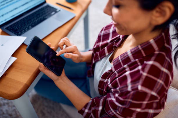 istock Close up of female entrepreneur using mobile phone while working at home. 2047878232