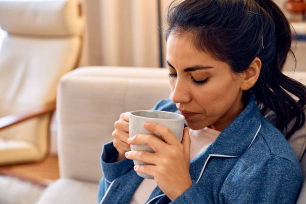 istock Hispanic woman having a cup of tea while relaxing at home. 2047881625