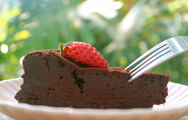 zbliżenie wilgotnego i aromatycznego ciasta czekoladowego bez mąki zwieńczonego świeżą truskawką - fudgy zdjęcia i obrazy z banku zdjęć