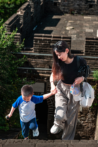 A beautiful lady and a little boy are playing on the Great Wall