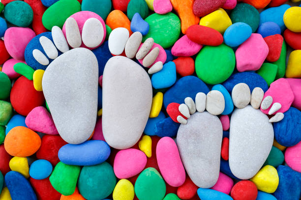 Two pairs of stone footprints on multi colored pebbles, top view