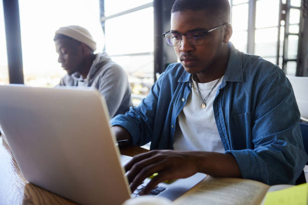 istock Young male college student doing homework on a laptop at school 2047935134