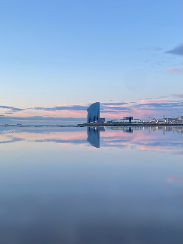 Reflection of the w hotel in Barcelona at sunrise with pink clouds