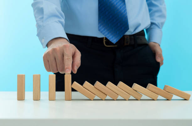 istock Businessman hand stopping the dominos falling 2047947256