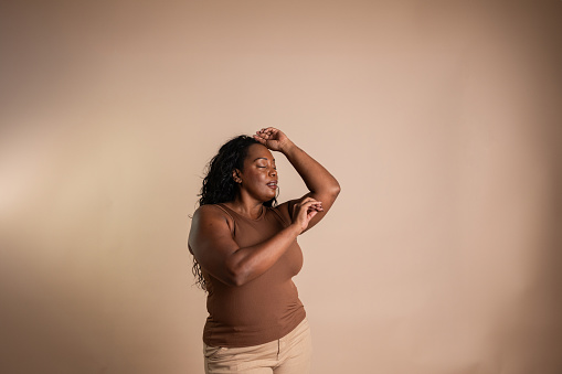 Mature woman dancing on a beige background