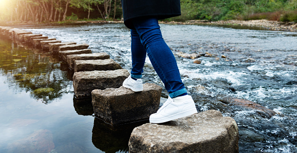 Woman crossing stepping stones on a river