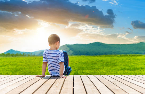 Little boy sitting on wooden sidewalk