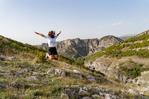 Young woman jumping on the rocky mountain in Serbia.