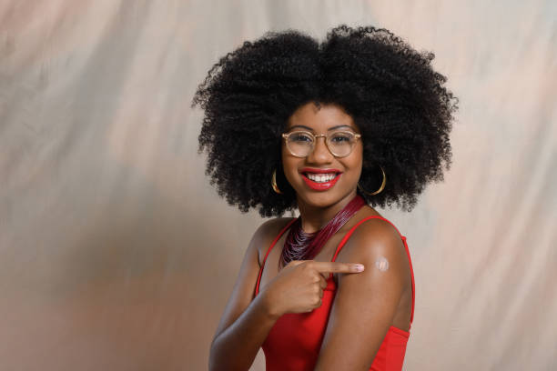 istock A woman points to the vaccine sticker on her arm, 2047968961