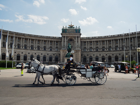 Vienna, Austria - August 16, 2023: A horse carriage carries tourist in a street in Vienna.