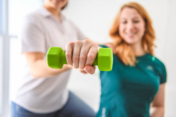istock Modern rehabilitation physiotherapy at work with client holding dumbbell 2047970579