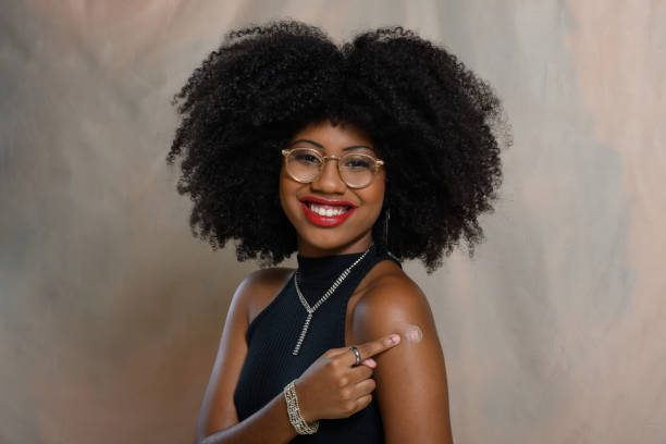 istock A woman points to the vaccine sticker on her arm, 2047974481