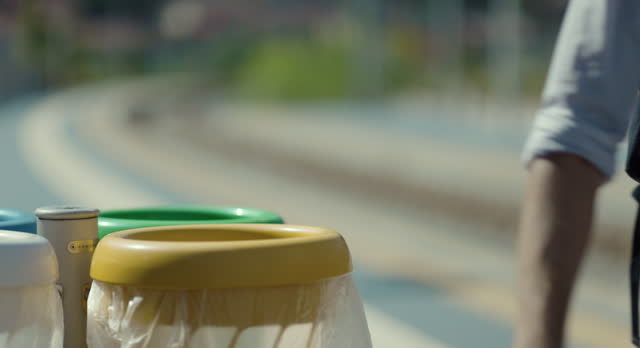 Separate waste collection: Person throws away waste on the platform train station.