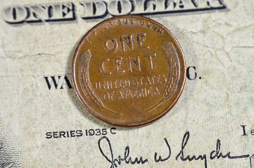 Two wheat ears surrounding lettering on the reverse side of One American cent coin series 1957, Obverse side features Abraham Lincoln the 16th president of USA, old USA vintage retro coin on old USD, selective focus