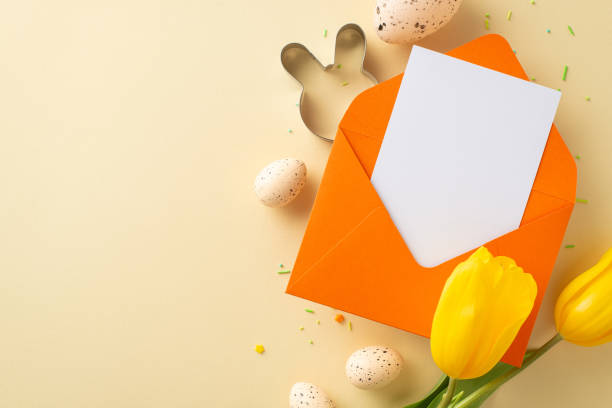 istock Pre-Easter excitement captured: overhead view showing a letter to the Easter bunny, colorful eggs, cookie cutter, sugar decorations, and tulips laid out on a pastel beige surface with space for words 2047995761