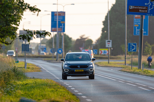 Netherlands, South Holland,  Alphen aan den Rijn, Benthuizen, June 7th 2023, young man in a Dutch gray 2022 Volkswagen T-Roc station wagon driving on the N209 road, just leaving a traffic circle at Benthuizen before sunset, the T-Roc is made by German  manufacturer Volkswagen since 2017, the N209 is a 26 kilometer long road in South Holland