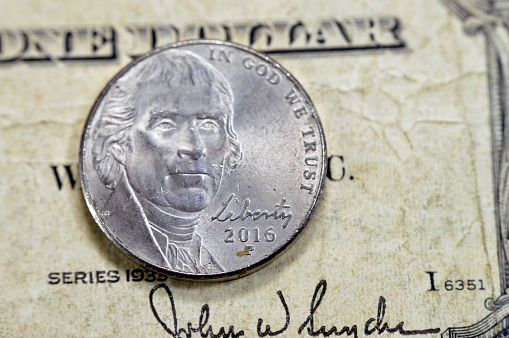 Obverse side of American money coin of 5 five cents 2016 coin features the 2nd portrait of Thomas Jefferson the founding father, 3rd president of the United States of America, on an old USD bill 1935, selective focus