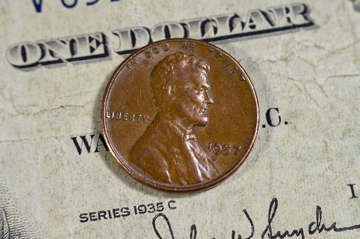 1 One American cent coin series 1957, Obverse side features Abraham Lincoln the 16th president of the United States Of America who preserved the Union, old USA vintage retro coin on old USD banknote, selective focus