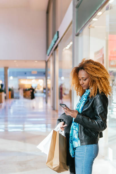 istock Young black woman writing text message in a shopping center 2048020777
